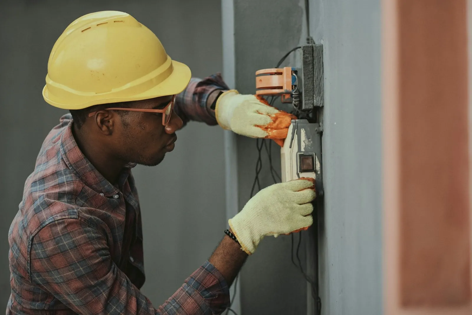 A technician in a hard hat working at an electrical panel