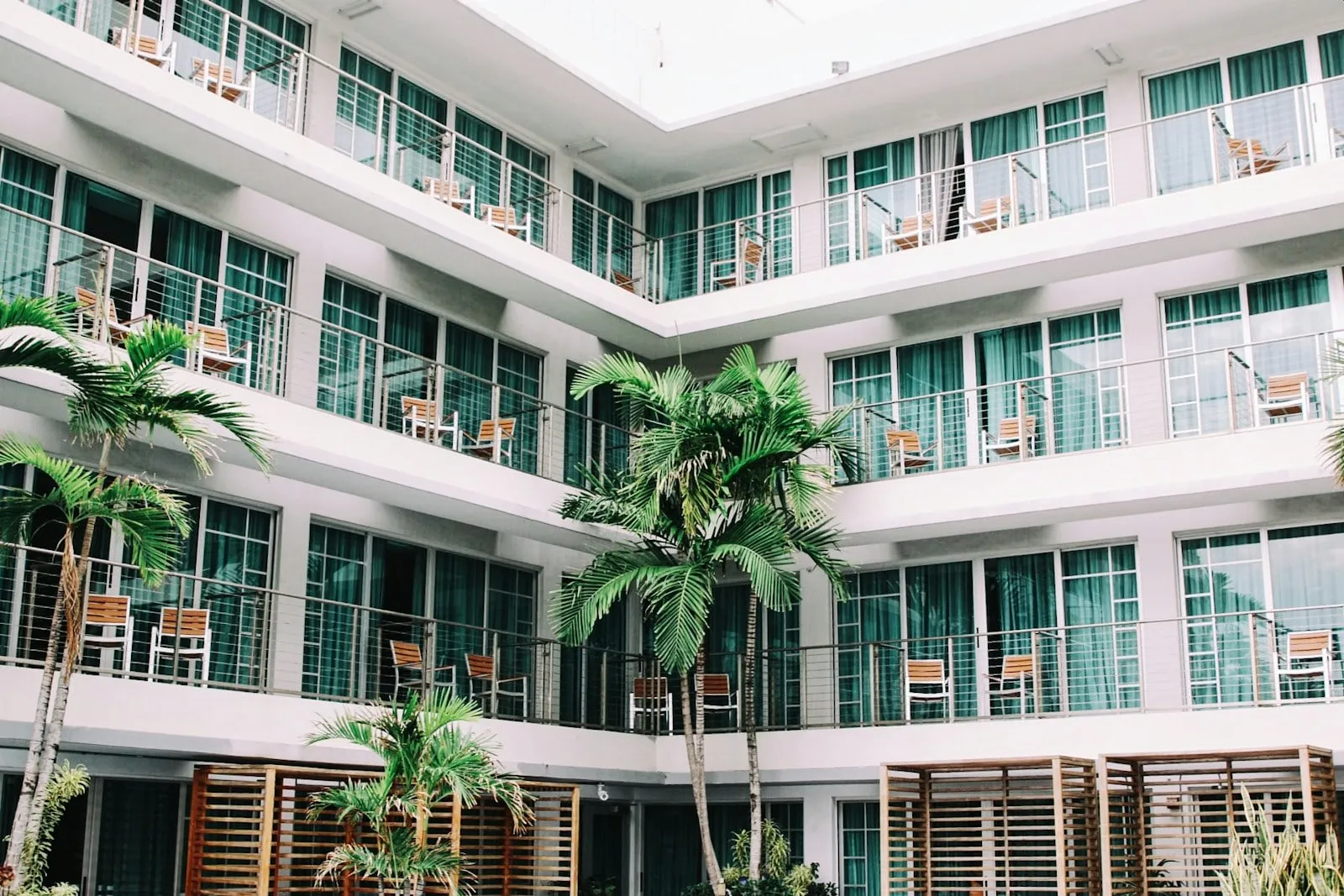 A white hotel building with balconies and palm trees