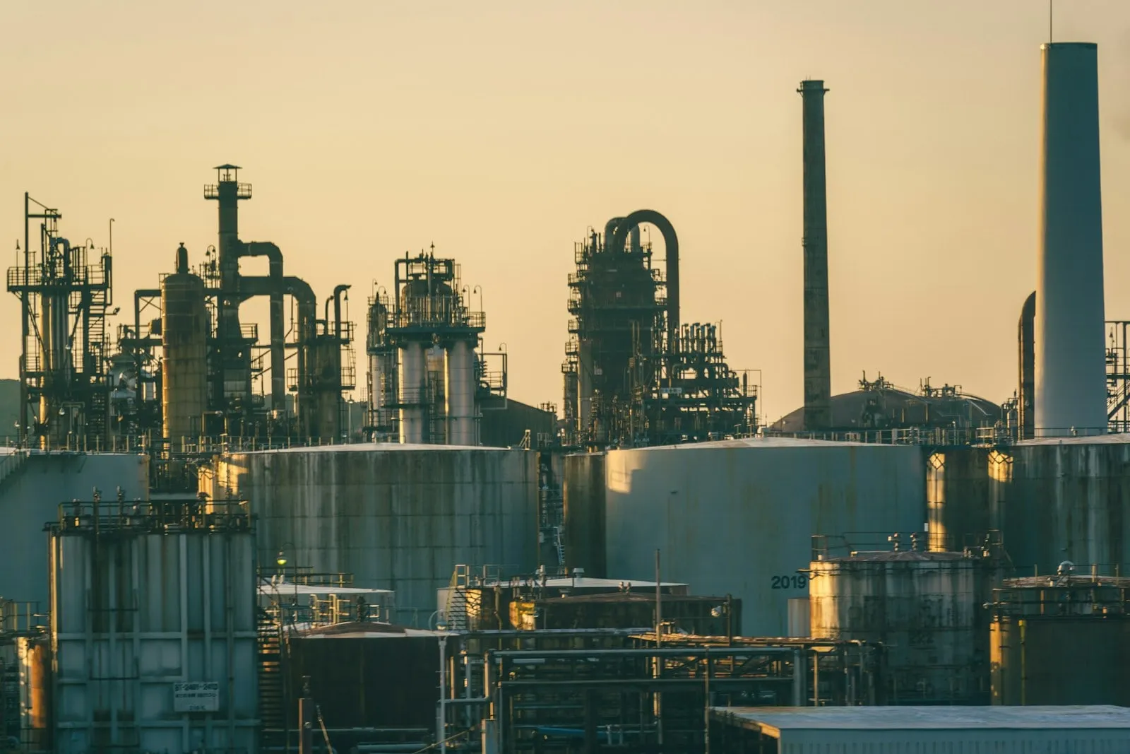 A refinery with storage tanks and pipework at sunset